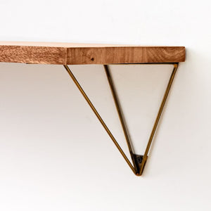 Triangle brackets on wall shelf - gold and wood - closeup